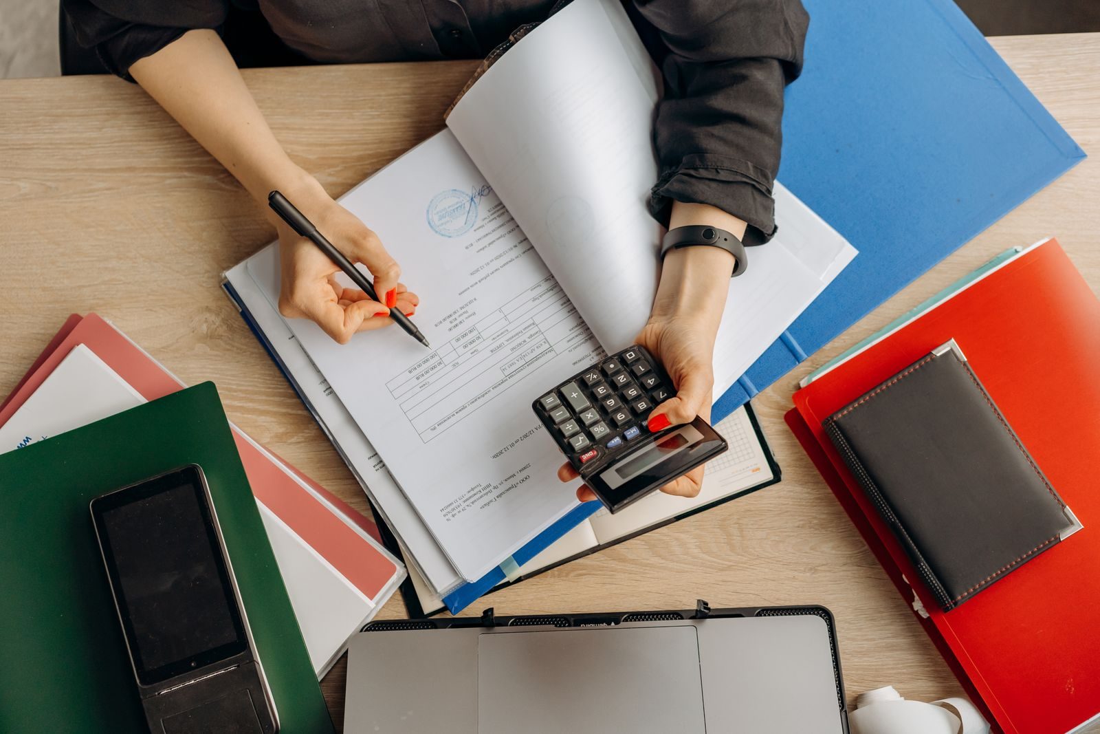 Contable revisando documentos financieros con una calculadora