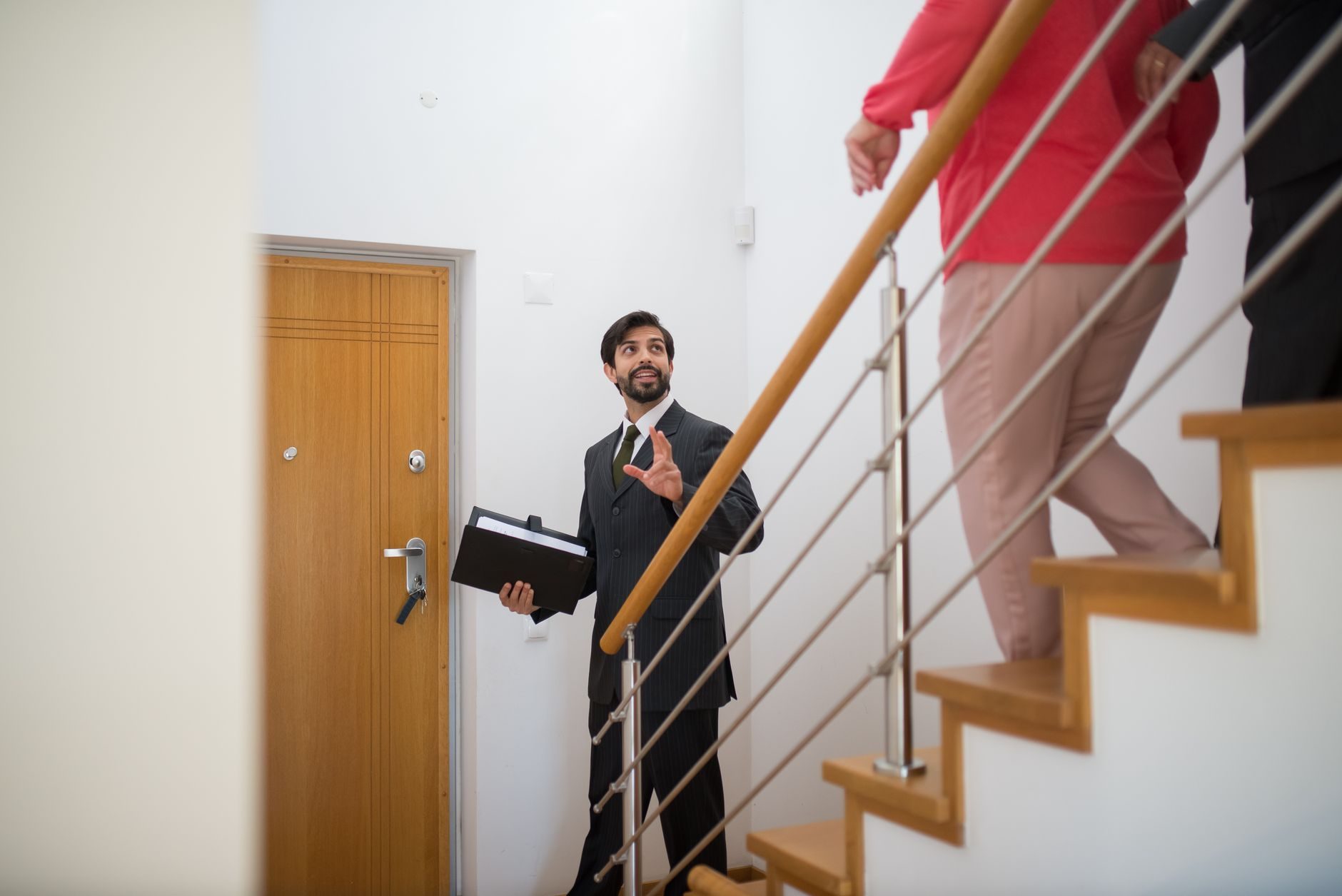 Un agente inmobiliario realizando una visita a una casa con compradores potenciales en las escaleras de una casa moderna.