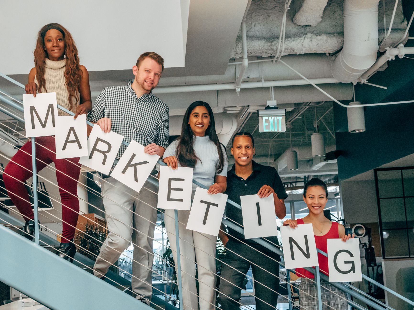Un grupo diverso de profesionales sosteniendo un cartel de marketing en un entorno de oficina moderno.